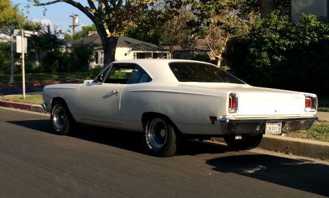 1968 Ford Mustang - White 1969 Plymouth Road Runner coupe seen from the rear, parked on a residential street.