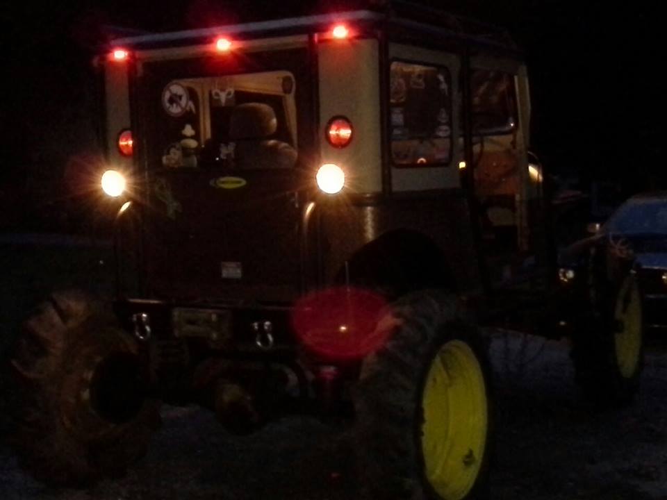 Off-road vehicle with large tires and yellow rims, rear view at night, red brake lights illuminated