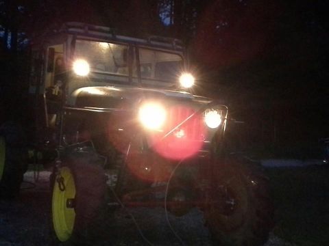Off-road vehicle with bright headlights on, seen at night. Yellow wheel hubs are visible