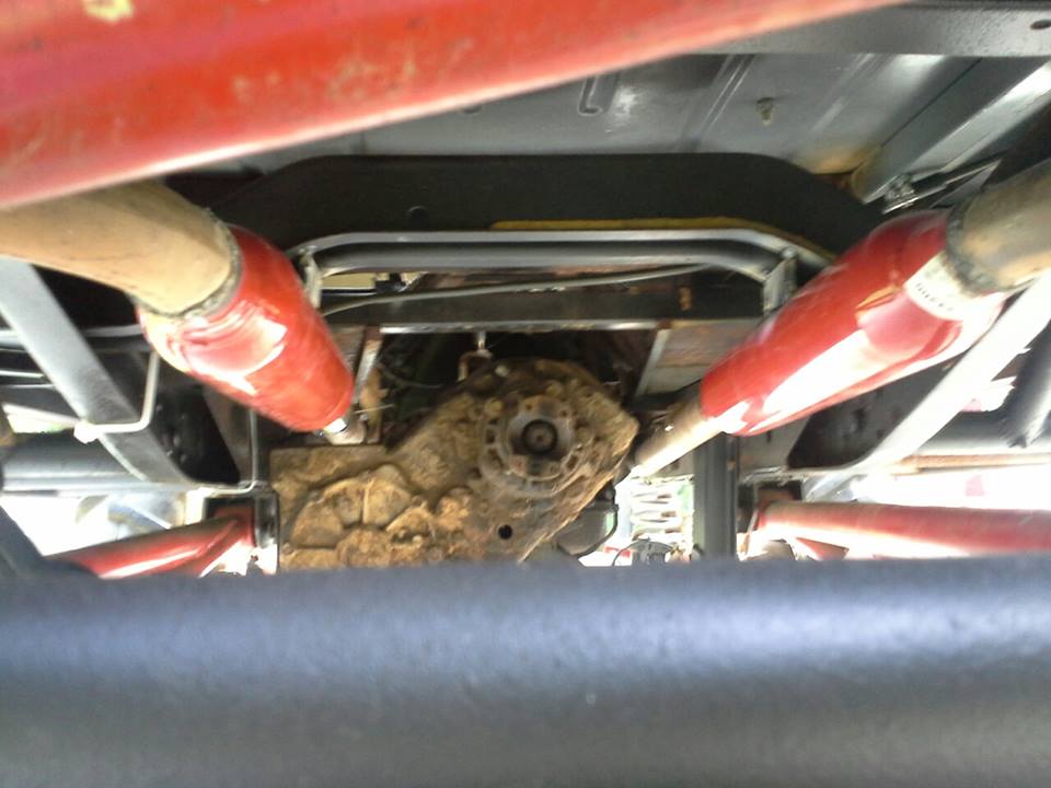 Undercarriage view of a vehicle's transfer case and dual exhaust pipes, one pipe is red
