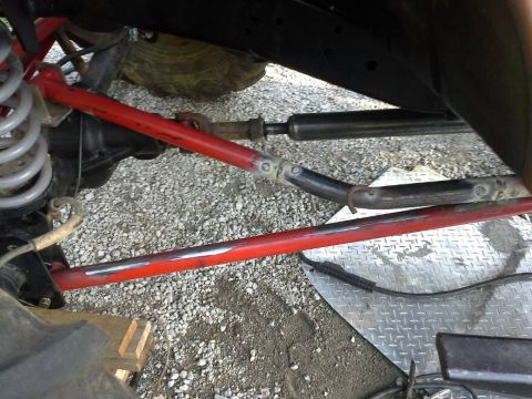 Close-up of red suspension components and steering linkage on a modified off-road vehicle