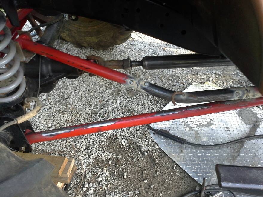 Close-up of red suspension components and steering linkage on a modified off-road vehicle