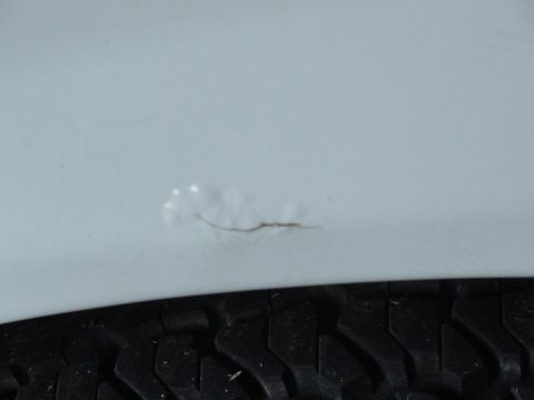 1990 Ford Bronco - Close-up of a tire and a scratched painted surface.