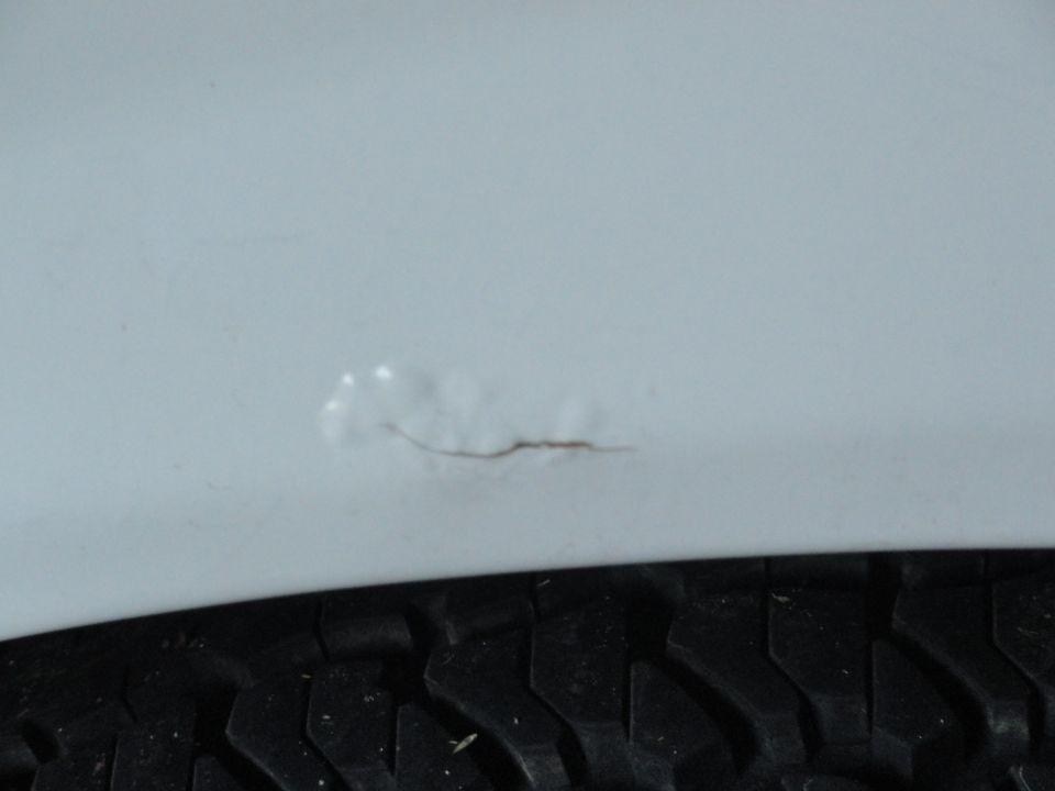 Tire tread and a light-colored painted surface with a scratch and paint chip
