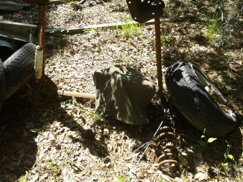 1978 Ford Bronco - Junked vehicle parts and tires are piled up outdoors.