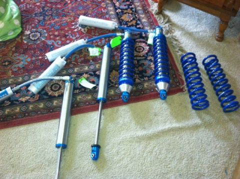 1995 Ford Bronco - A collection of aftermarket suspension components, including shocks and springs, are displayed on a patterned rug.