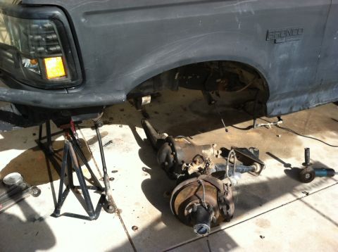 1995 Ford Bronco - Rear axle and suspension parts from a 1995 Ford Bronco are disassembled and on the floor.