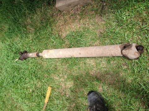 1979 Ford Bronco - A driveshaft lies on the grass, showing signs of rust and wear.