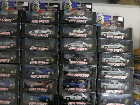 1991 Ford LTD Crown Victoria - Collection of boxed RoadChamps Collectibles toy police cars, many appearing to be Ford Crown Victorias.
