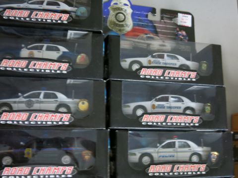 1991 Ford LTD Crown Victoria - A collection of boxed Road Champs toy police cars is displayed, various models and markings.