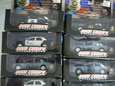 1991 Ford LTD Crown Victoria - A collection of Road Champs collectible police car models are displayed in their packaging.