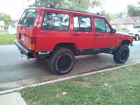 1986 Ford Bronco - This red Jeep Cherokee XJ is parked on the side of a residential street.