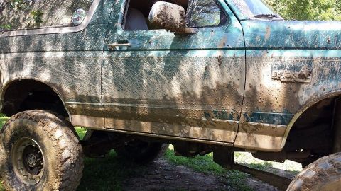 1996 Ford Bronco - This 1996 Ford Bronco is heavily coated in mud, suggesting it has been used for off-roading.