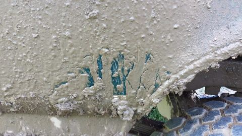 1996 Ford Bronco - A close-up of a heavily mud-splattered vehicle panel reveals chipped teal paint and a portion of the tire.