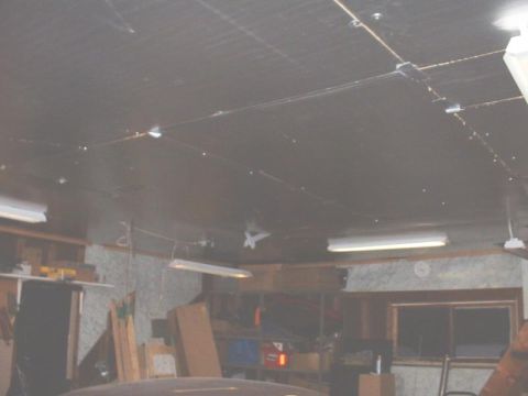 1986 Ford Bronco - A view of a cluttered garage interior, fluorescent lighting and various stored items.