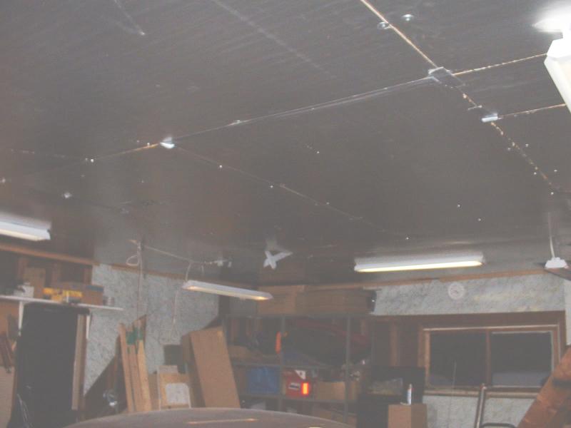 Dim garage ceiling with fluorescent shop lights over cluttered workshop shelves