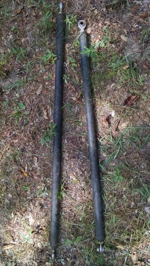 1978 Ford Bronco - Two black shock absorbers with metal ends are visible on the ground.