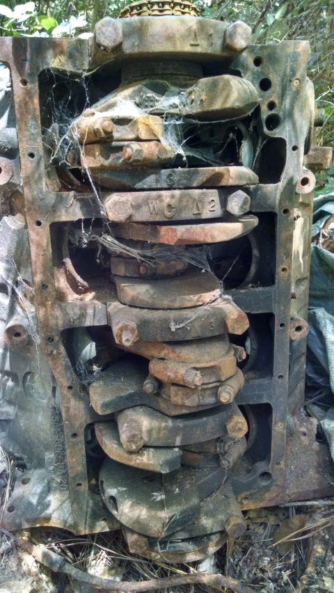 1978 Ford Bronco - Engine block with crankshaft and connecting rods, heavily rusted and covered in cobwebs.