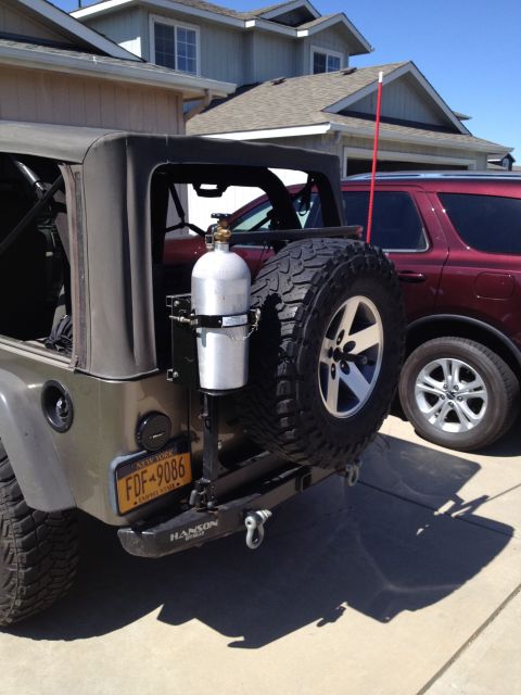 2005 Jeep Wrangler - Rear view of a Jeep Wrangler equipped with a spare tire carrier and an external tank, parked next to another vehicle.