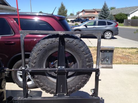 2005 Jeep Wrangler - A custom-built spare tire carrier is shown, attached to the rear of a vehicle. Another SUV is parked nearby.