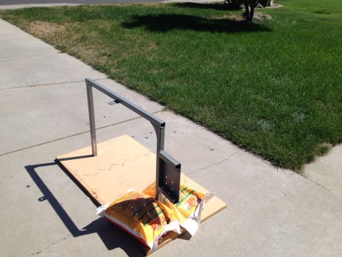 2005 Jeep Wrangler - A metal rack assembly is shown outdoors on a sidewalk, secured to a plywood base with weights.