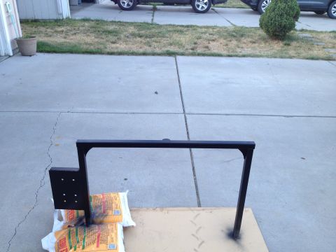 2005 Jeep Wrangler - A black metal rack is shown on a driveway, with two vehicles parked in the background.