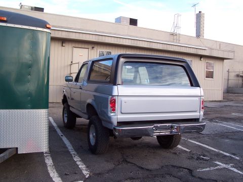 1990 Ford Bronco - This 1990 Ford Bronco is seen from the rear, parked beside a green trailer in a lot.
