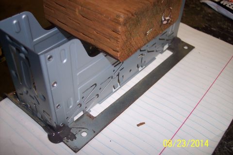 1978 Ford Bronco - A metal bracket is held down by a wooden block on a piece of lined paper.