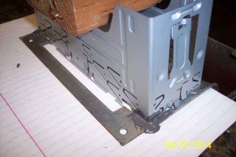 1978 Ford Bronco - A metal bracket, possibly for a car stereo, is being held in place by a wood block and sealant.