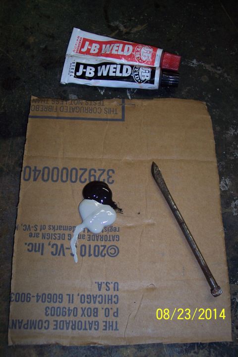1978 Ford Bronco - Two tubes of J-B Weld and a nail sit next to a dollop of mixed epoxy on a piece of cardboard.