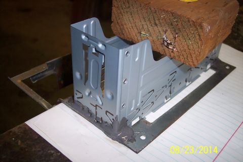 1978 Ford Bronco - A metal bracket assembly is held in place by a wooden block, with visible text from a website at the bottom right.