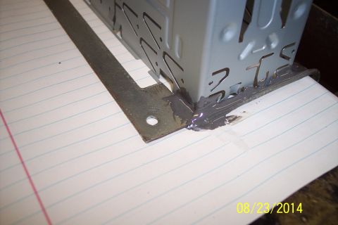 1978 Ford Bronco - A metal bracket is secured with sealant to a perforated housing on a piece of lined paper.