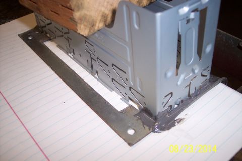 1978 Ford Bronco - A metal bracket, possibly for a car radio, is secured with a wood block and sealant.