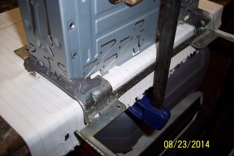 1978 Ford Bronco - Close-up of a metal bracket being held by a clamp, likely during a repair or fabrication process.