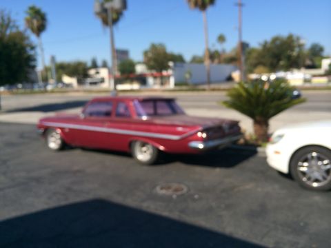 1968 Ford Mustang - A red 1961 sedan is parked next to a white vehicle on a sunny day.