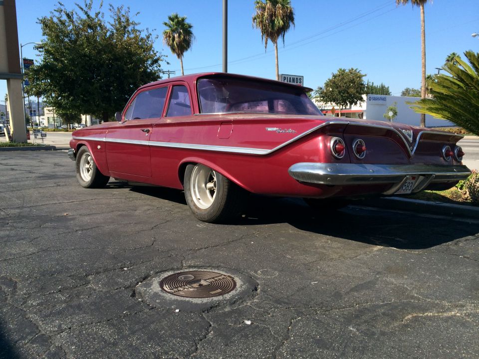 Red 1961 Chevrolet sedan with a rear spoiler and dual taillights