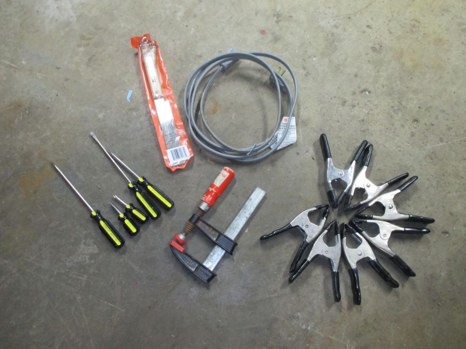 Assorted tools: screwdrivers, clamps, and a cable on a concrete floor