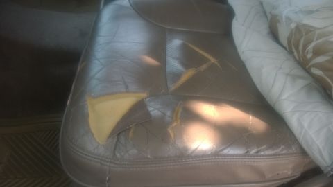 1996 Ford Bronco - The leather upholstery on this car seat is significantly damaged, revealing the yellow foam underneath.