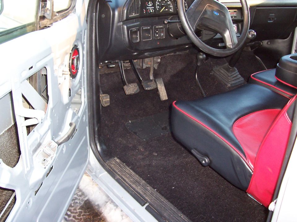 Interior of a 1990 Ford Bronco with black and red seats and a manual transmission