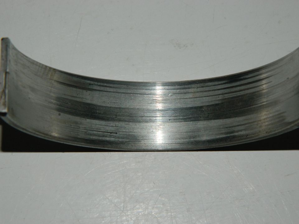 Worn engine bearing with visible scoring and wear marks