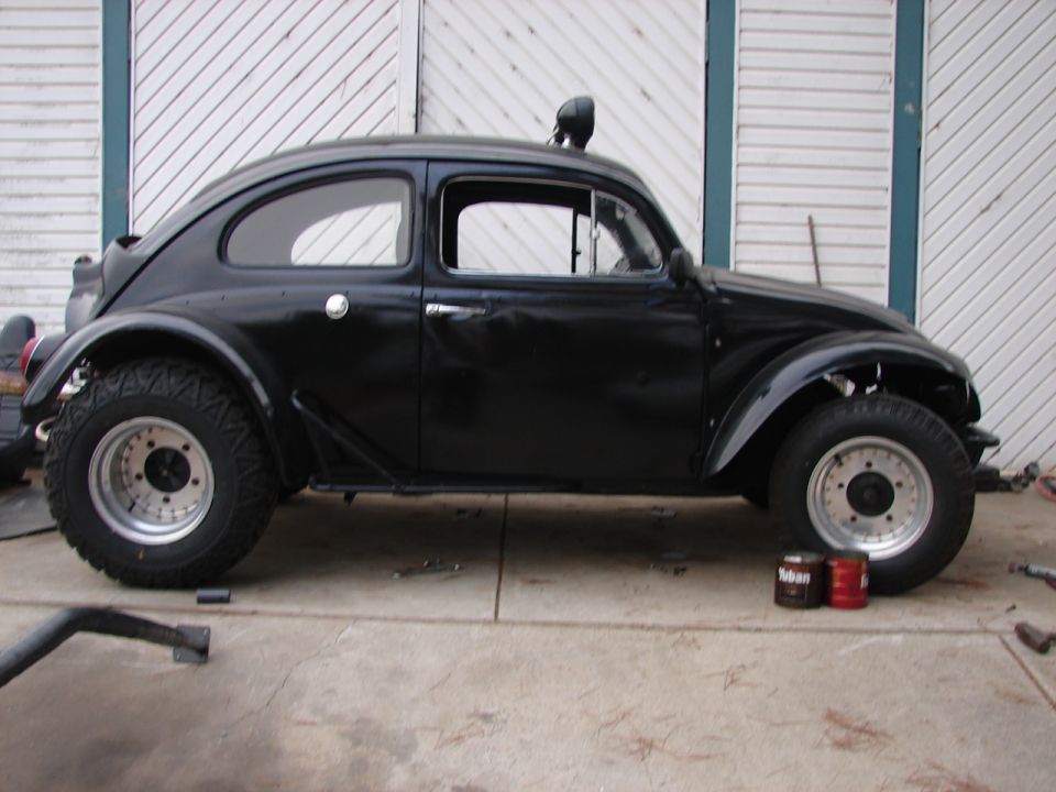Black Volkswagen Beetle with off-road tires and custom roll cage, side view