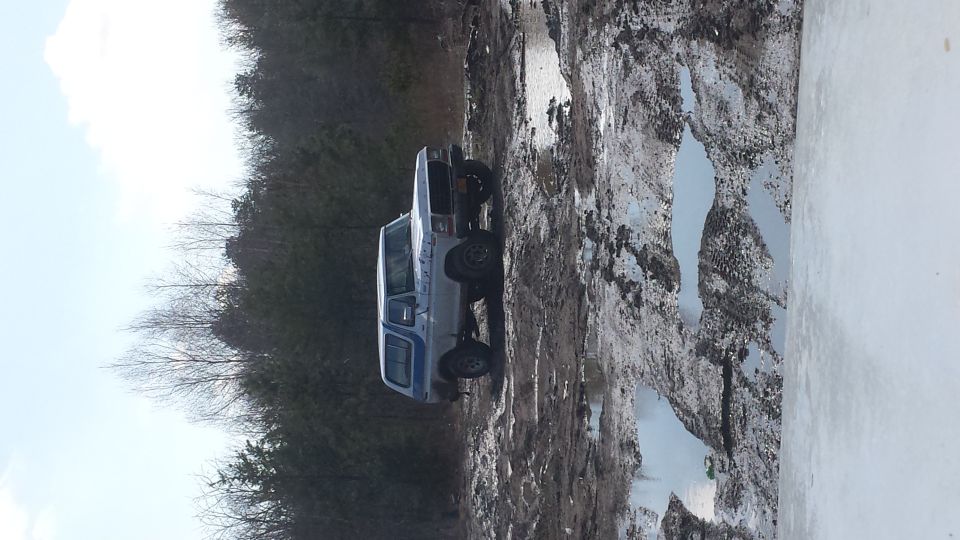 Light blue 1978 Ford Bronco with blue stripe, stuck in mud, side view