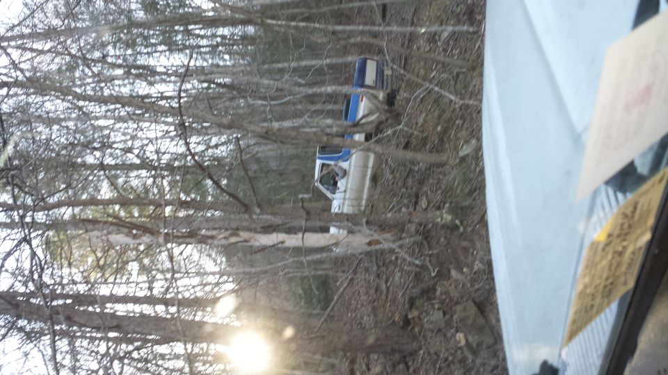 two pickup trucks parked on a wooded trail, one white and blue, the other white