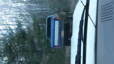 1979 Ford Bronco - A blue SUV is parked outdoors, partially obscured by trees and a white structure.