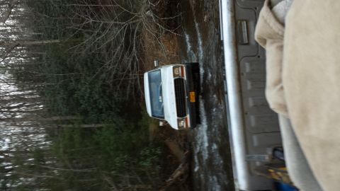 1979 Ford Bronco - A white van navigates a muddy, wooded trail, its front grille visible.