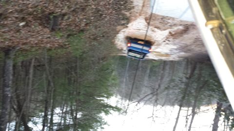 1979 Ford Bronco - A blue SUV navigates a muddy path surrounded by trees.