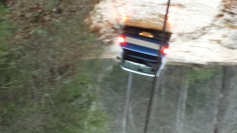 1979 Ford Bronco - A blue SUV navigates through a water-filled path, its taillights illuminated.