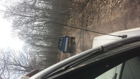 1979 Ford Bronco - Two vehicles travel down a wooded dirt road, kicking up dust.