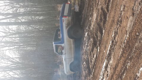 1979 Ford Bronco - A pickup truck navigates a muddy trail with trees in the background.