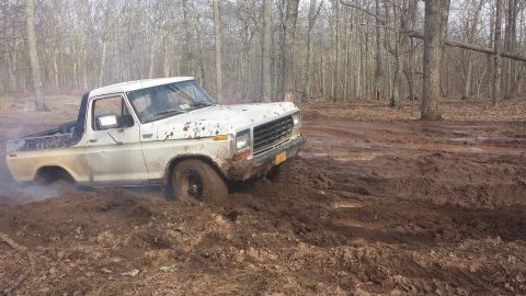 1979 Ford Bronco - White Ford Bronco stuck in mud on a wooded trail.